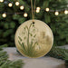 A round ornament featuring a snowy owl and a church in the background, surrounded by greenery and twinkling lights.