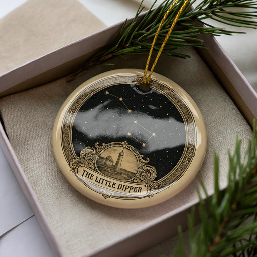 A decorative ornament in a box, featuring a starry night sky and a lighthouse, with the text "The Little Dipper" on it.