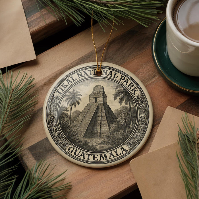 A decorative ornament featuring the image of the Mayan pyramid at Tikal National Park in Guatemala, surrounded by pine branches and a cup of coffee.