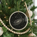 A Christmas tree decorated with ornaments, including a circular ornament with a spiral galaxy design and a wooden bead garland.