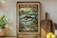 a framed vintage postage stamp with an illustration of a tuna fish, placed on a shelf next to a wooden cutting board and some lemons.