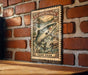 A metal sign with a painting of a salmon fish is mounted on a brick wall.