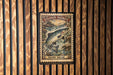 A metal plate with a printed image of a salmon fish, mounted on a wooden wall.