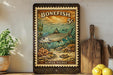 A vintage-style postage stamp featuring a bonefish, with the text "BONEFISH 5c" and "ALBU VULPES" printed on it. The stamp is displayed on a shelf next to a wooden cutting board and a potted plant.