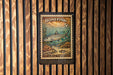 A metal stamp with a fish illustration and text, hanging on a wooden wall.