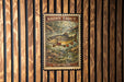A framed print of a brown trout is displayed on a wooden wall.