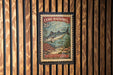 A vintage-style stamp featuring a mackerel fish, with the text "Cero Mackerel 25¢" and "Scobornorous regalis" printed on it. The stamp is displayed on a wooden wall with vertical slats.