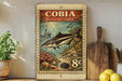 a vintage-style stamp or postcard with a fish illustration, placed on a wooden surface next to a wooden cutting board and some lemons.