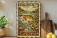 A framed U.S. postage stamp depicting a cutthroat trout, with a wooden paddle and a potted plant in the background.