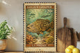 A vintage postage stamp featuring a large fish swimming in a coral reef, with the text "GOLIATH GROUPPER 20¢" and "U.S. POSTAGE" printed on it. The stamp is displayed on a shelf next to a wooden cutting board and a potted plant.