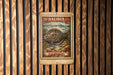 A metal stamp with a colorful illustration of a fish, placed on a wooden wall.