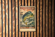 A U.S. postage stamp featuring a fish, specifically a Mahi Mahi, is displayed on a wooden wall.