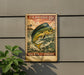 A vintage U.S. postage stamp featuring a fish, mounted on a wall next to a plant.
