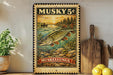 A vintage-style metal sign featuring a fish illustration and the text "Musky 5¢" is displayed on a shelf next to a wooden cutting board and a potted plant.