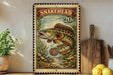 A framed print of a fish, specifically a snakehead, is displayed on a shelf next to a wooden cutting board and some lemons.