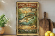 A vintage-style postage stamp featuring a speckled trout, with a price of 10 cents, is displayed on a wall next to a wooden cutting board and some kitchen utensils.
