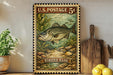 A framed vintage postage stamp depicting a striped bass fish, placed on a shelf next to a wooden cutting board and some lemons.