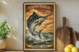 A framed vintage postage stamp featuring a striped marlin fish, with a price of 20 cents, is displayed on a wall next to a wooden cutting board and a potted plant.