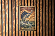 A metal sign with a striped marlin fish on it, mounted on a wooden wall.