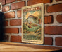 A vintage postage stamp featuring a fish, likely a freshwater fish, is displayed on a brick wall.