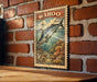 A vintage-style stamp depicting a fish, likely a Wahoo, is mounted on a brick wall.