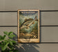 A weathered, vintage-style postage stamp featuring a fish, mounted on a wall next to a plant.
