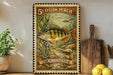 A vintage-style postage stamp featuring a yellow perch fish, placed on a wooden surface next to a wooden cutting board and a potted plant.