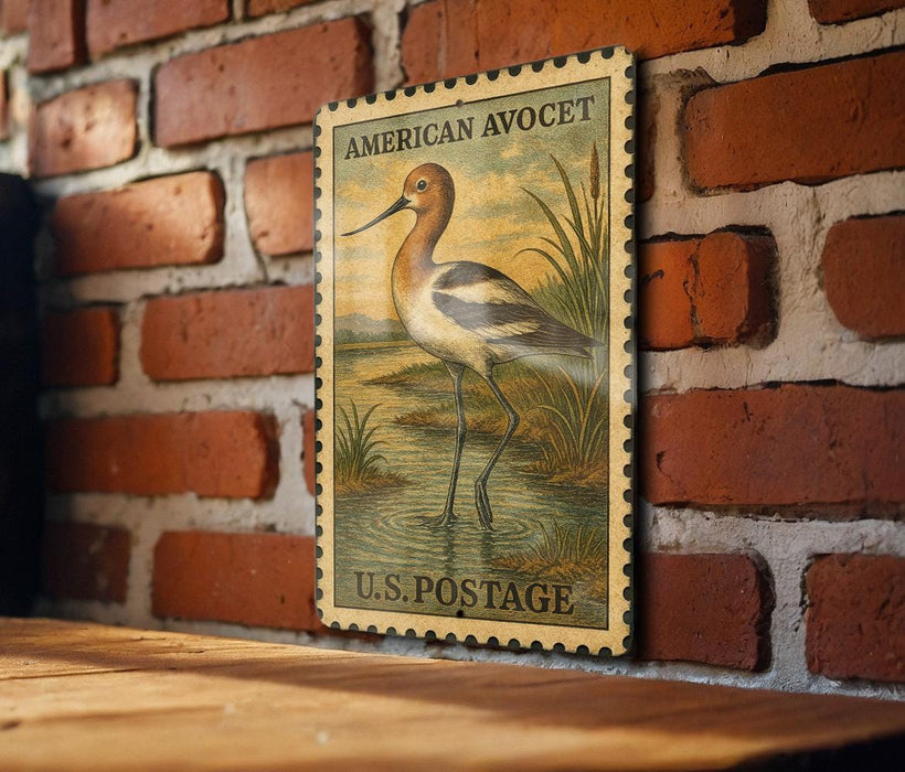 A vintage American Avocet postage stamp is displayed on a brick wall, featuring a detailed illustration of the bird in a natural setting.