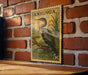 A vintage postage stamp featuring a large bird, likely a heron, perched on a branch against a brick wall.