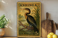 A vintage postage stamp featuring a large bird, likely a heron, is displayed on a shelf next to a wooden cutting board and some lemons.