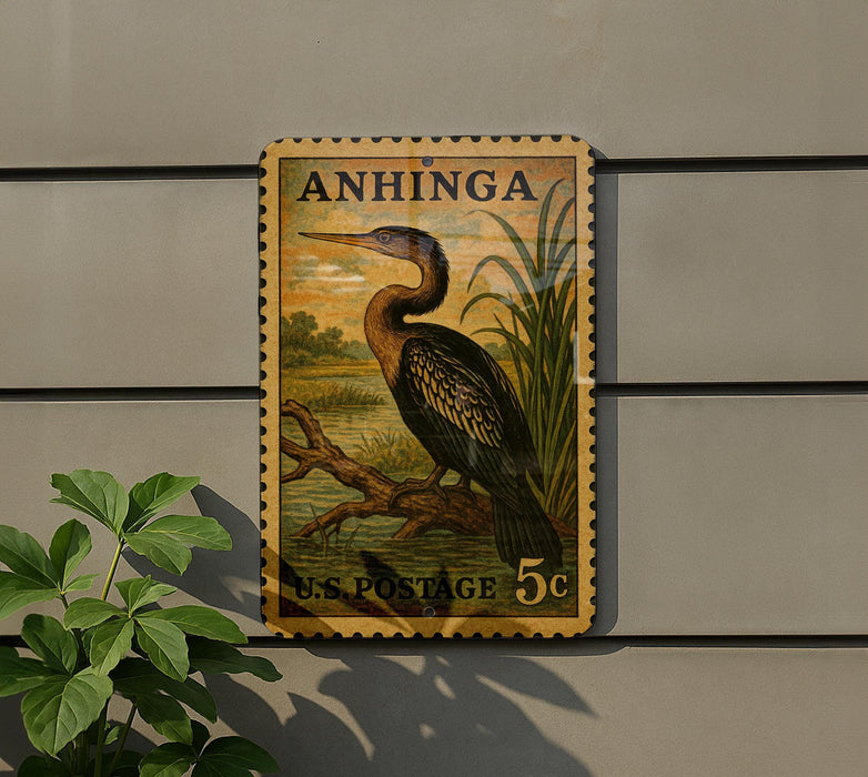 A vintage postage stamp featuring a large bird, likely a heron, perched on a branch. The stamp is mounted on a wall and is surrounded by greenery, including a plant.