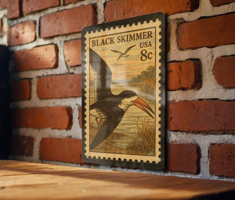 A vintage-style postage stamp featuring a black skimmer bird is displayed on a brick wall.