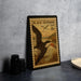 A framed postage stamp depicting a black skimmer bird is displayed on a table next to some black camera lenses.