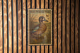 A postage stamp featuring a blue-winged teal duck, which is a type of waterfowl. The stamp is mounted on a wooden wall with vertical slats.