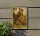 A postage stamp featuring a bohemian waxwing bird is displayed on a wall, with a plant visible to the left.