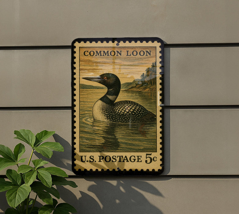 A vintage-style postage stamp featuring a loon swimming in a body of water, mounted on a wall.