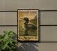A vintage-style postage stamp featuring a loon swimming in a body of water, mounted on a wall.