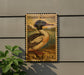 A wooden sign with a postage stamp design, featuring a bird, is mounted on a wall next to a plant.
