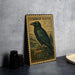 a framed illustration of a black raven perched on a rock, with a vintage-style border.