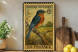 A vintage-style postage stamp featuring a bluebird perched on a branch, with a wooden cutting board and a potted plant in the background.