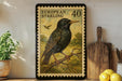 A framed European starling postage stamp is displayed on a shelf, with a potted plant, wooden cutting board, and lemons nearby.