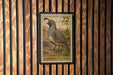 A 22-USA postage stamp featuring a quail bird is displayed on a wooden wall.