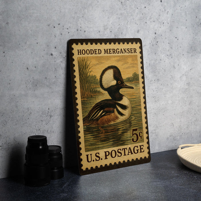 A U.S. postage stamp featuring a hooded merganser duck, with the text "HOODED MERGANSER" and "5¢" printed on it.