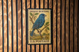 A vintage U.S. postage stamp featuring a blue bird perched on a branch, with the text "INDIGO BUNTING" and "U.S. POSTAGE" printed on it.