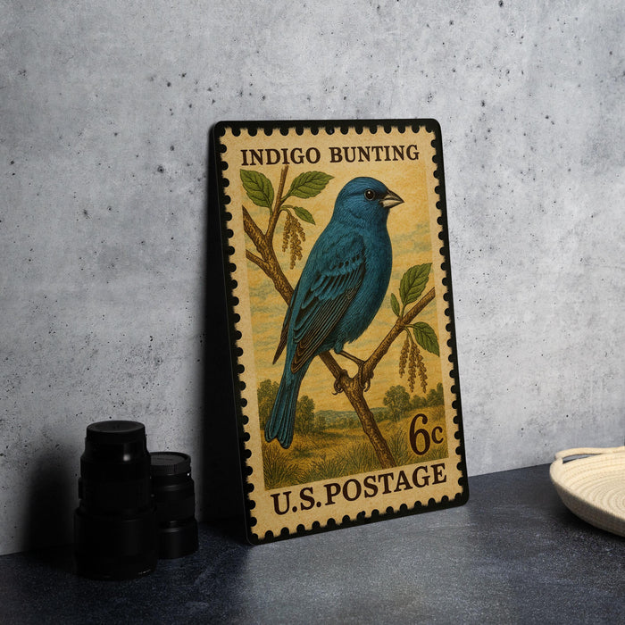 A vintage U.S. postage stamp featuring a blue bird perched on a branch, with the text "INDIGO BUNTING" and "U.S. POSTAGE" printed on it.