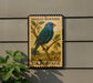 A vintage postage stamp featuring a blue bird perched on a branch, mounted on a wall.