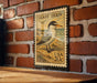 A vintage-style postage stamp featuring a bird, likely a tern, is displayed on a brick wall.