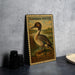 A vintage postage stamp featuring a duck, placed on a gray surface next to some black camera lenses.