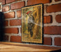A framed illustration of a woodpecker is mounted on a brick wall, with a wooden table below it.