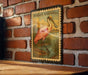 A vintage-style metal stamp depicting a pink spoonbill bird is mounted on a brick wall.